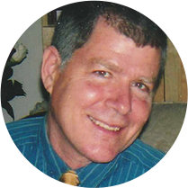 Smiling man with striped shirt indoors.